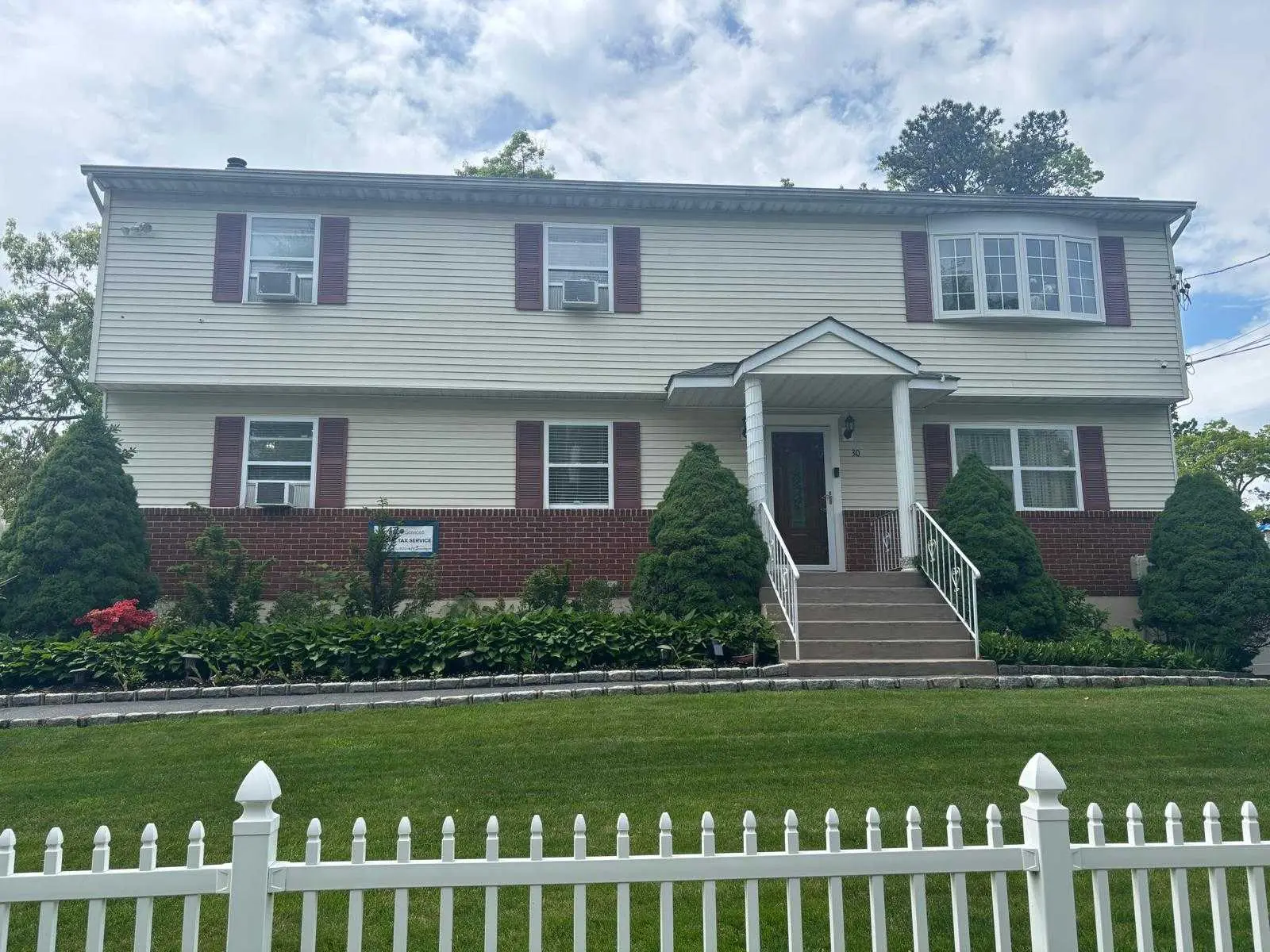 <p>Generate a realistically detailed image of a revamped two-story suburban house. This home should be in the traditional Colonial style, now with upgraded features. Modifications include a newly added porch extending 10 feet forward and 20 feet wide, a pathway made of stone leading up to the entrance, contemporary double front doors, and grand floor-to-ceiling windows replacing the old bay window. The landscape around the house should be embellished with ornamental grasses and flowers matching the current season. On one side, add a horizontal wood slat fence in a natural finish, creating a harmonious blend of modern and classic aesthetics.</p>